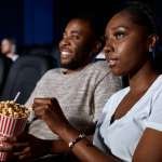 African couple eating popcorn in cinema